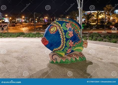 Night View Of A Decoratively Painted Abstract Stone Fish Sculpture On