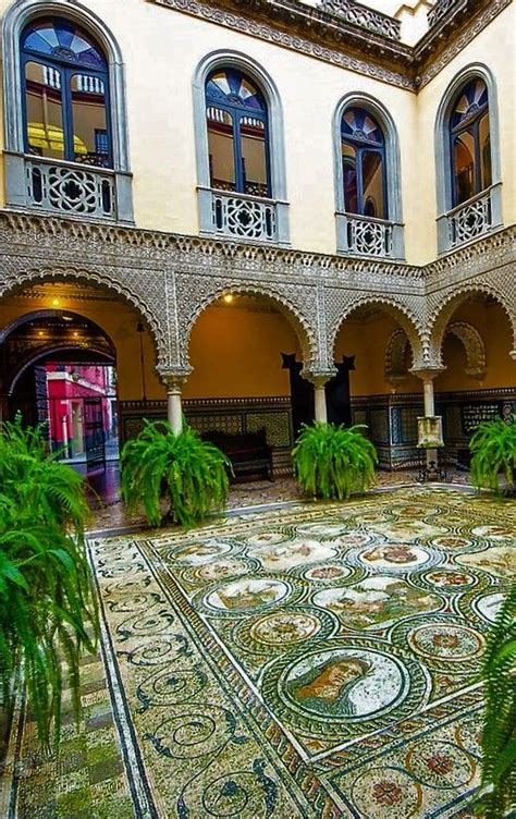 An Ornate Courtyard With Palm Trees And Potted Plants In The Foreground