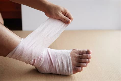 Hand Is Wrapping Bandage Around Sprain Ankle Injury Foot Treatment