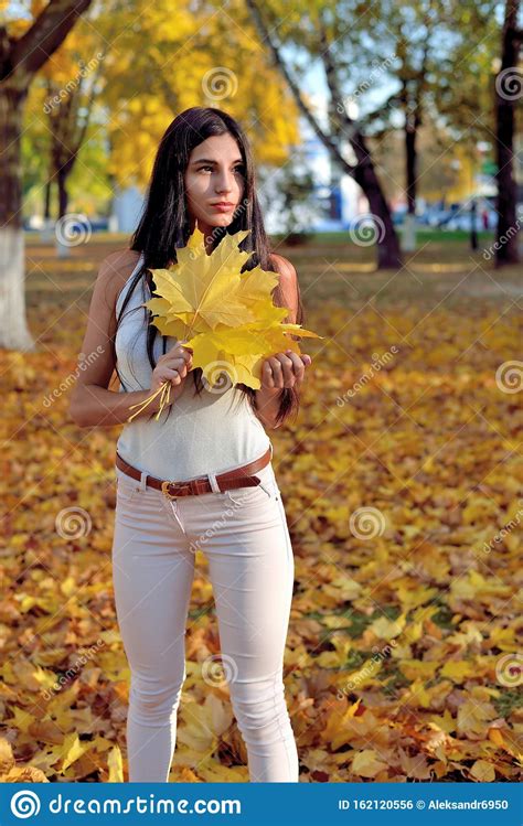 Beautiful Girl In Autumn Park Holding A Maple Leaf In Her Hand Smiling