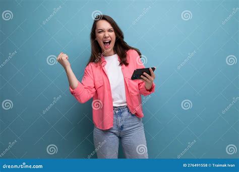 Happy Lucky Brunette Woman In Informal Look With Smartphone On Studio Background Stock