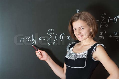 Young Teacher Is Standing Near Blackboard In Classroom Stock Image