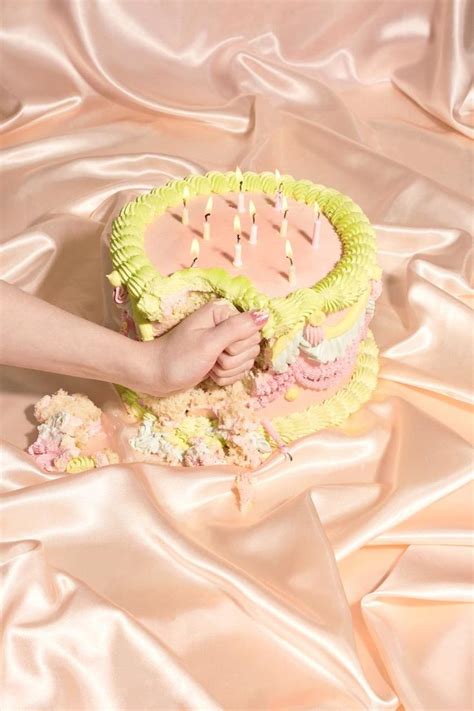 A Person Is Decorating A Cake With Yellow Icing And Pink Flowers On It