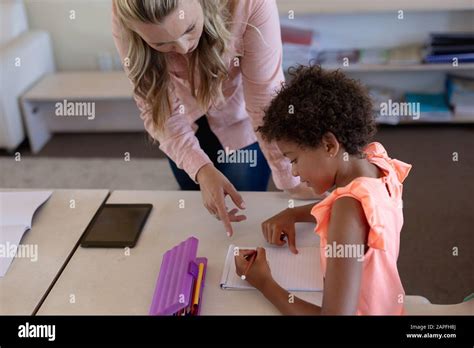 Female Teacher With Long Blonde Hair Helping A Schoolgirl In A Classroom Stock Photo Alamy