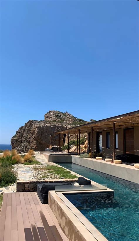 An Outdoor Swimming Pool With Wooden Decking Next To The Ocean And