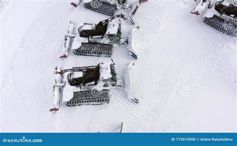 Red Snowcat Standing On Snowy Parking Lot At Winter Ski Resort In