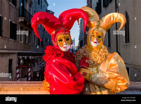 Portraits Of Two Masked People In Beautiful Harlequin Costumes Celebrating The Venetian