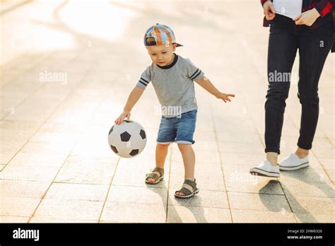 Mom And Son Play Football Together Outdoors In The Park Little Boy