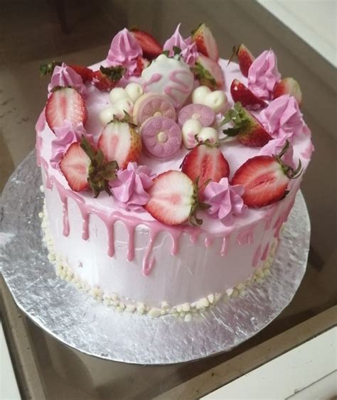 A Strawberry Cake With Pink Icing And Flowers On Top