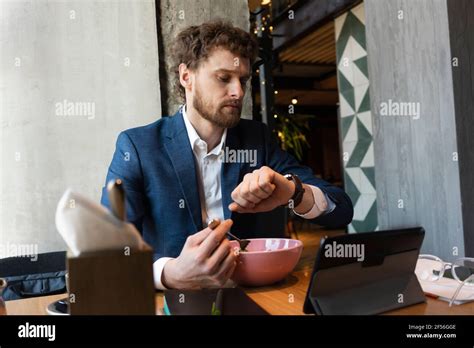 Male Owner Checking Time While Having Food Sitting With Digital Tablet