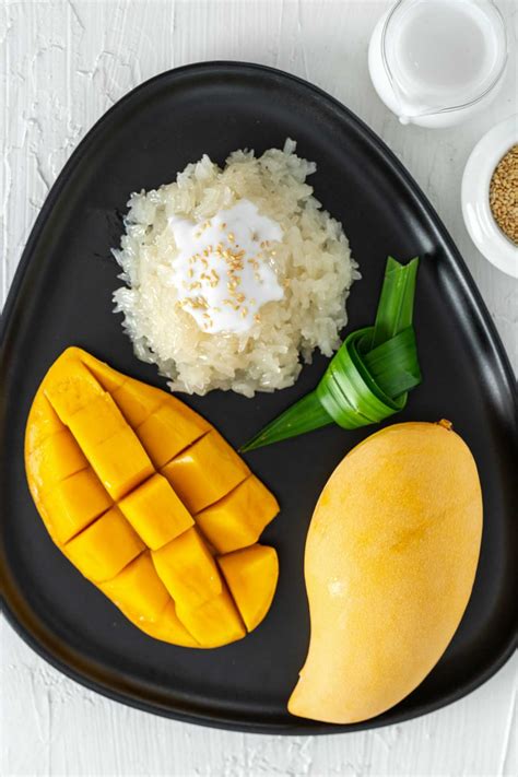 a black plate topped with mangoes, rice and other food on top of a ...