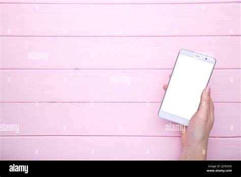 Female Hands Holding Mobile Phone With Blank Screen On Pink Wooden