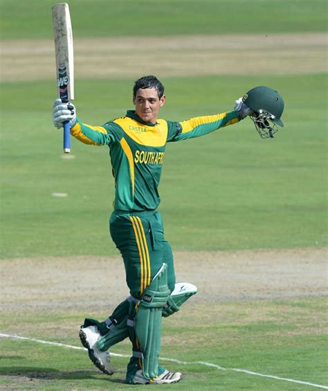 A Man In Green And Yellow Uniform Holding A Bat On Top Of A Grass Field