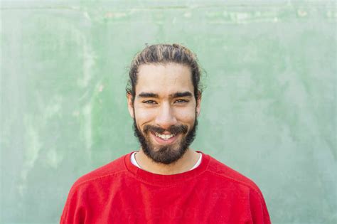 Portrait Of Bearded Young Man Wearing Red Sweatshirt In Front Of Green