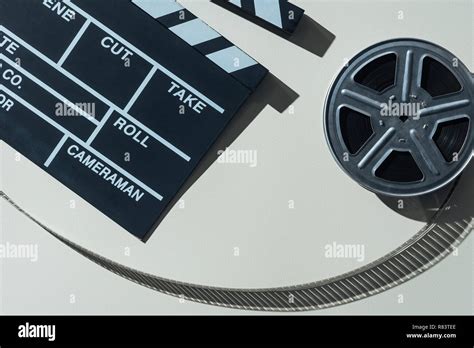 Top View Of Clapperboard And Film Reel With Cinema Tape On Grey