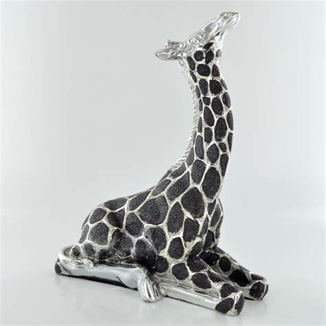 A Giraffe Figurine Sitting On Top Of A Silver Object In Front Of A