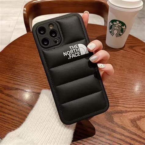 A Woman S Hand Holding Up A Phone Case With The North Face Logo On It