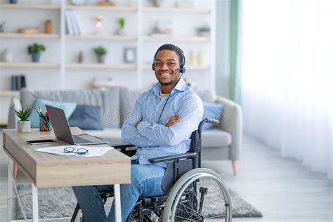 Paraplegic Black Guy In Wheelchair With Documents Using Laptop To Work