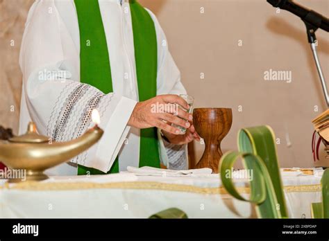 Priest Wearing A Green Chasuble Preparing The Chalice For The