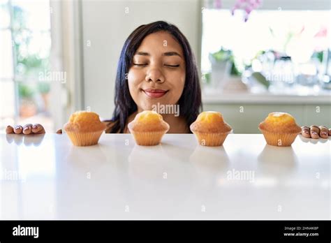 Hispanic Brunette Woman Smelling Muffins At The Kitchen Stock Photo Alamy