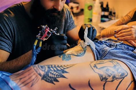 L Artiste Masculin De Tatouage Barbu Fait Un Tatouage Sur Une Jambe