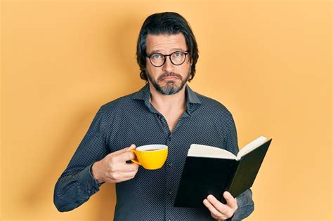 Premium Photo Middle Age Caucasian Man Reading Book Drinking Cup Of