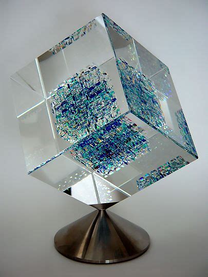 A Glass Cube Sculpture Sitting On Top Of A Metal Stand