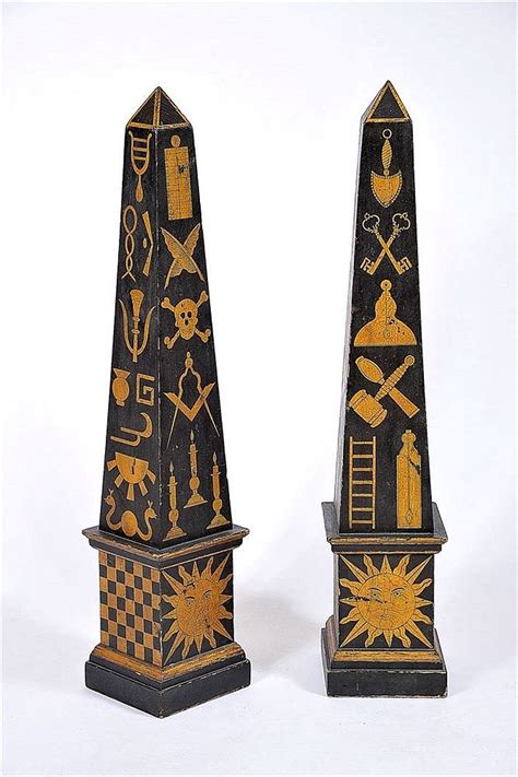 Two Black And Gold Obelisk Standing Next To Each Other On A White