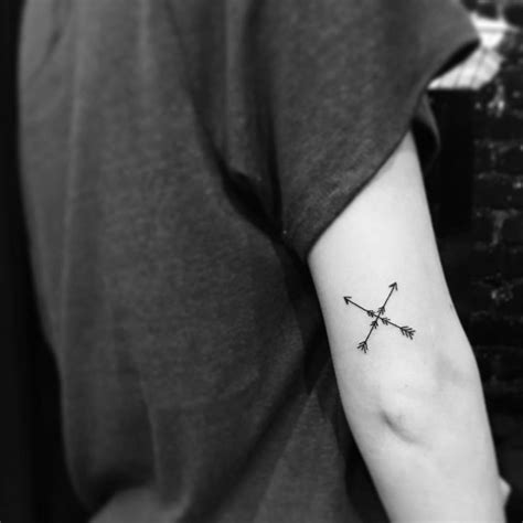 Minimalistic crosse arrows tattoo located on the