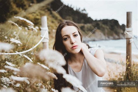 Tender Brunette Woman By Flowers On Coast Natural Emotionless