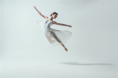 Elegant Ballet Dancer In White Dress Jumping In Studio Stock Photo