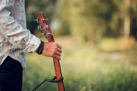 Premium Photo Midsection Of Man Holding Guitar In Park