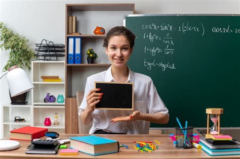 Sonriente Joven Profesora De Matem Ticas Sentada En Un Escritorio Con