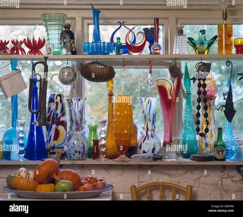 Collection Of Colourful Glass Bottles And Vases On Window Shelves Stock