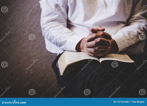 Hands Folded In Prayer On A Holy Bible In Church Concept For Faith