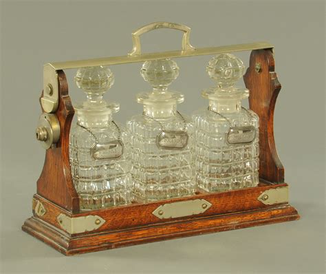 An Edwardian Oak Tantalus Stand With Three Decanters And With Silver