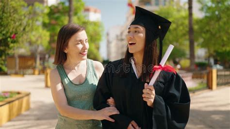 Two Women Mother And Graduated Daughter Holding Diploma Kissing At