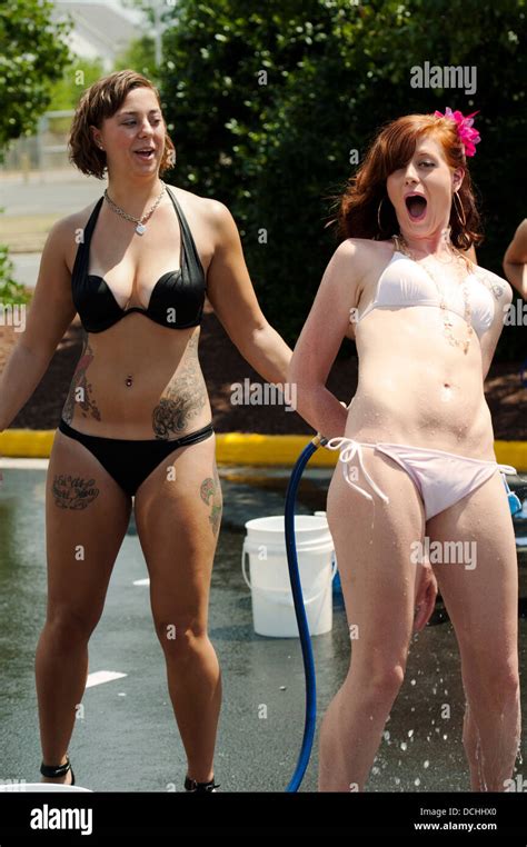 Two Women In Bikini Swimsuits Having Fun With A Garden Hose Stock Photo