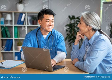 Happy Mature Japanese Male Doctor Shows Laptop Talk On Consultation To