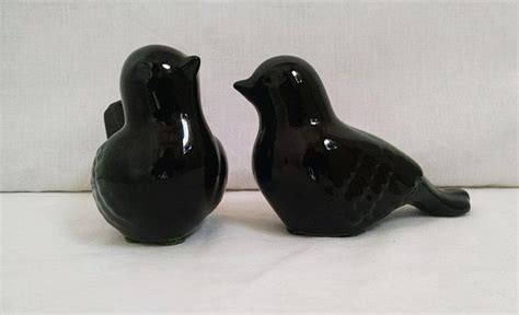 Two Black Ceramic Birds Sitting Next To Each Other