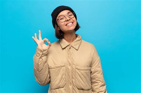 Mujer latina joven que se siente feliz relajada y satisfecha mostrando aprobación con gesto
