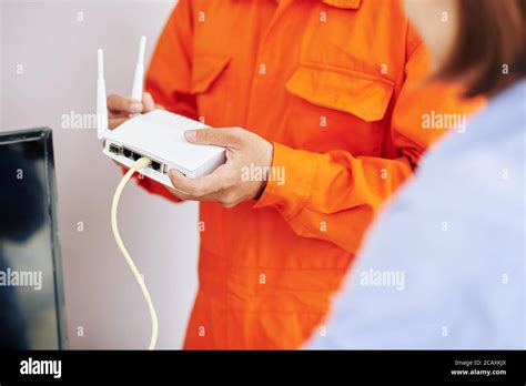 Close Up Image Of Electrician Explaining Woman How To Use Wi Fi Router He Just Installed Stock