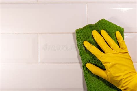 Hand In A Yellow Rubber Glove Wiping The Ceramic Tile Surface With A