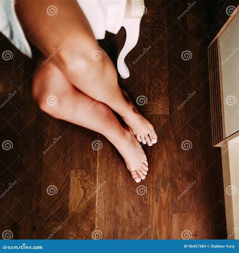 The Beautiful Bride In A White Robe Is Sitting On A Chair Slim Suntanned And Nude Legs Of A