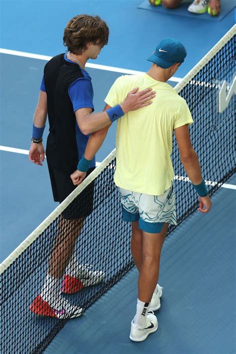 Two Men Standing On A Tennis Court Holding Racquets And Talking To Each