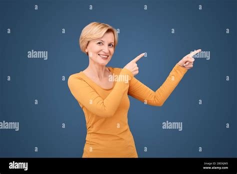 Freestyle Mature Woman Standing Isolated On Blue Pointing Aside At