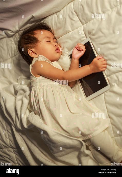 baby sleeping on bed after playing digital tablet Stock Photo - Alamy