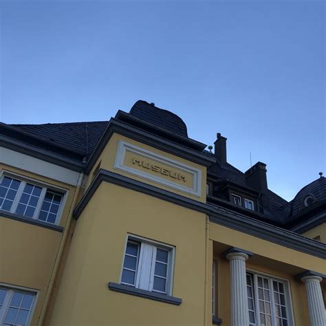 A Yellow Building With White Windows And Columns On The Top Floor