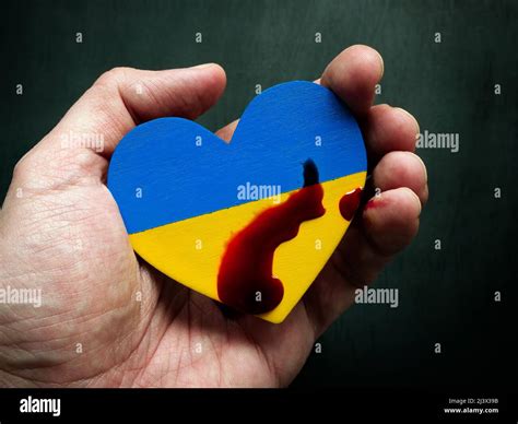 Eine Hand hält ein Herz in den Farben der Flagge der Ukraine mit einem