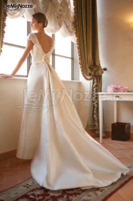 A Woman Standing In Front Of A Window Wearing A White Dress With A Bow